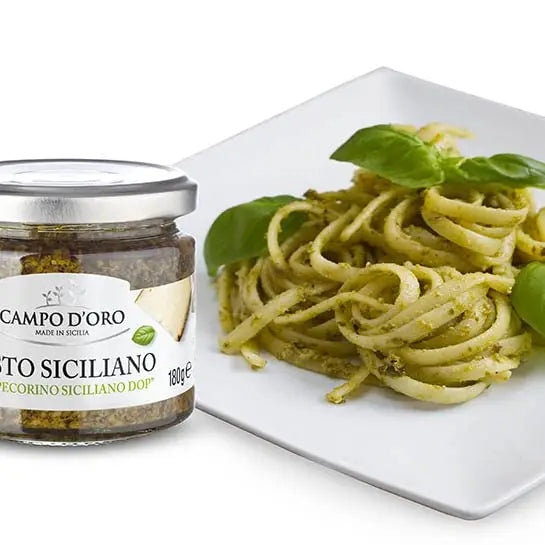 Jar of Campo d'oro pesto siciliano with a plate of pasta on a white background