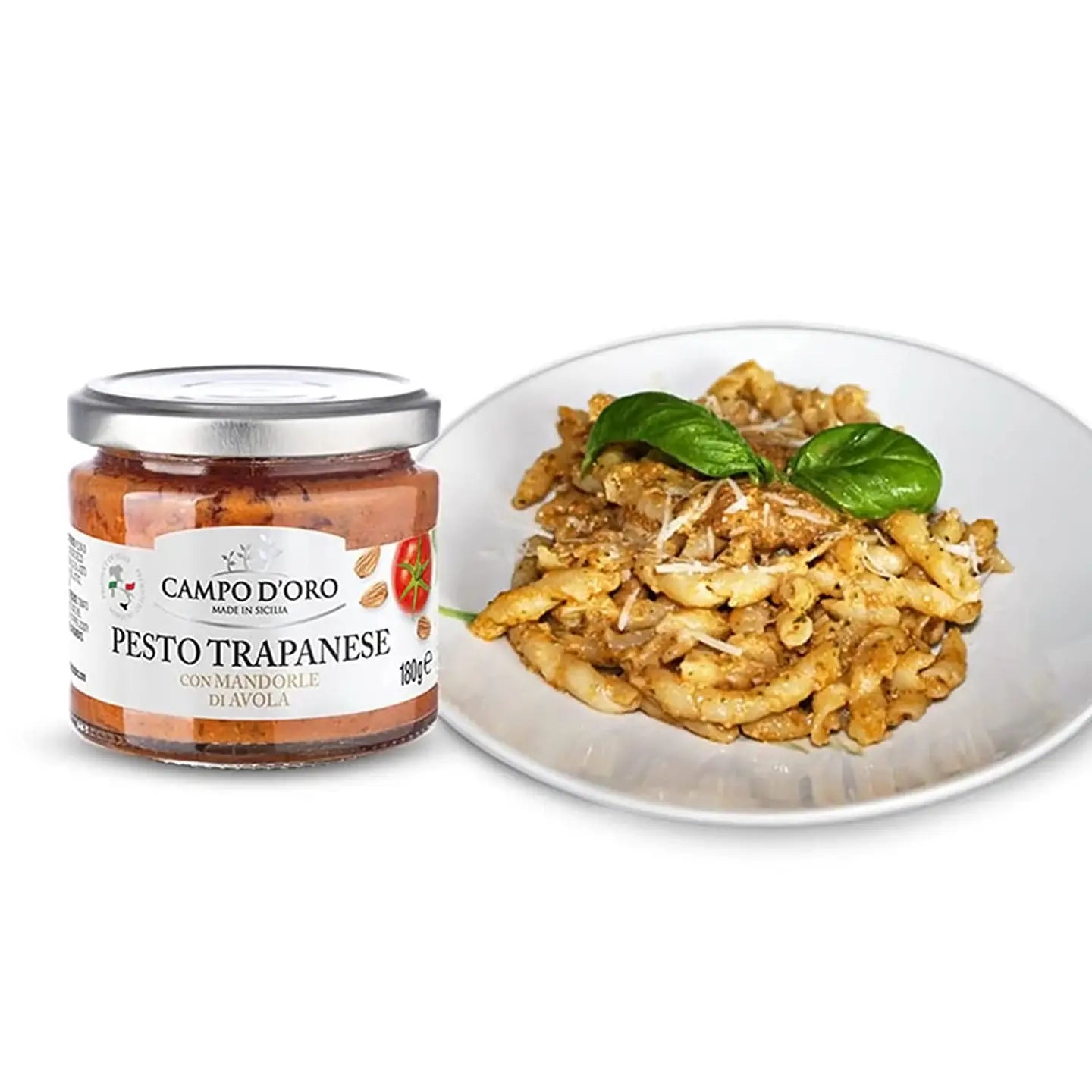 Jar of Campo d'Oro Pesto Trapanese next to a plate of pasta with basil leaves on a white background